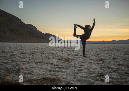 Gesamte Länge der jungen Frau tun Yoga in der Wüste bei Sonnenuntergang, Death Valley, Nevada, USA Stockfoto