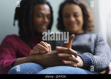 Liebendes Paar Hand in Hand beim Sitzen zu Hause Stockfoto