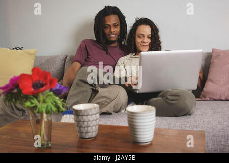Multi-ethnischen Pärchen mit Laptop sitzend auf Sofa zu Hause Stockfoto