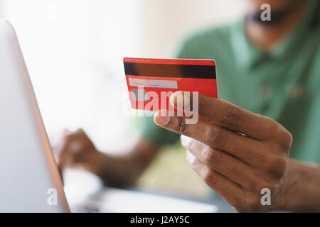 Bild der Mann, der Kreditkarte beim Online-shopping durch Laptop zu Hause hält beschnitten Stockfoto