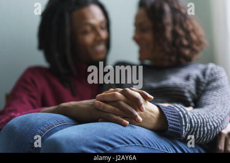 Romantisches Paar Hand in Hand beim Sitzen zu Hause Stockfoto