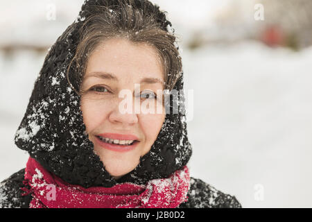 Porträt der lächelnde ältere Frau in Winterkleidung mit Schnee bedeckt Stockfoto