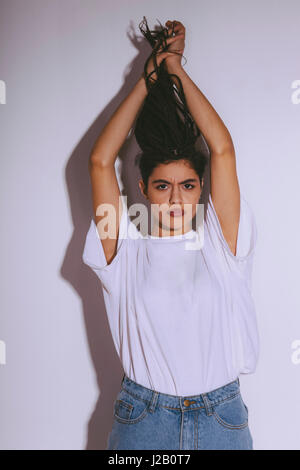 Porträt von schöne Mode Model Holding Dreadlocks stehend vor weißem Hintergrund Stockfoto