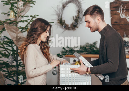 Seitenansicht der lächelnde paar Verpackung Weihnachtsgeschenke zu Hause Stockfoto