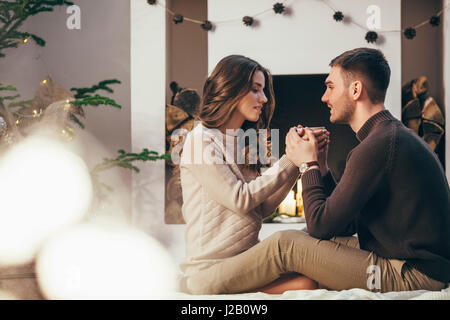 Romantisches Paar Kaffeetrinken beim Sitzen zu Hause während der Weihnachtszeit Stockfoto