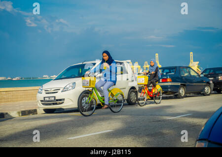 George Town, Malaysia - 10. März 2017: Schöne malerische Aussicht auf unbekannte muslimische Frauen Reiten Fahrräder entlang der Esplanade, eine Lage am Wasser im Herzen der Stadt. Stockfoto