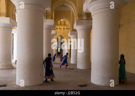 Eine Gruppe von Mädchen spielen zwischen den Pfeilern des Thirumalai Nayakkar Mahal palace Stockfoto