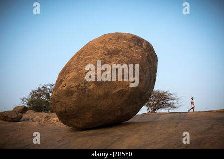 Ein Mann geht durch die gigantischen Felsen namens Krishnas Butterball Stockfoto