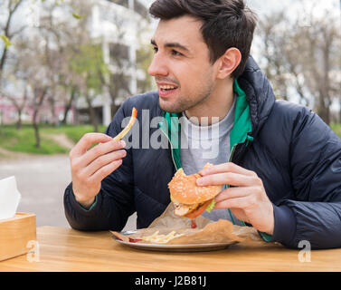 Mann isst einen Burger mit Pommes frites im Speiselokal café Stockfoto