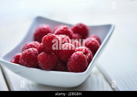 Frisch und leicht unvollkommen Himbeeren in eine Schüssel auf Tafel Tisch weiß Stockfoto
