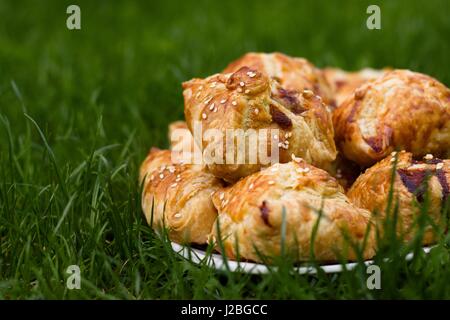 Hausgemachte Pasty mit Hackfleisch-Fleisch-Füllung, mit Sesam bestreut und serviert im Freien an einem sonnigen Tag Stockfoto