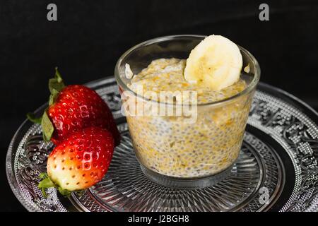 Glastasse leckere und gesunde Banane Chia Pudding. Dekoratives Glas Platte Funktionen spiegeln in der Tasse. Stockfoto