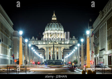 Blick auf den beleuchteten St. Peter Basilika, die Straße Via della Conciliazione und leichte Spuren von Autos in Rom, Italien Stockfoto