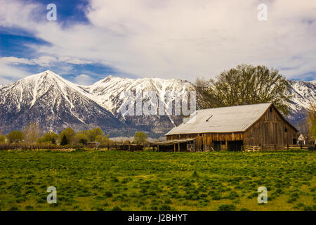 Alte rustikale Scheune im Tal unter Schnee bedeckt die Berge Stockfoto