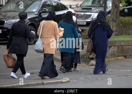 Asiatischen afrikanischen Flüchtlings gekleidet Burka Hijab Schal auf der Straße in die UK alltägliche Szene fünf junge Mädchen zu Fuß in Menge Kaffee trinken Stockfoto