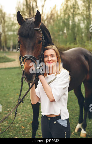 Schönes Mädchen kommuniziert mit einem Pferd im park Stockfoto