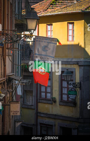 Altstadt von Porto Portugal, Ansicht einer portugiesischen Nationalflagge, die von einem Lichtwellenstrahler in einer schmalen Straße in der Gegend von Ribeira in Porto, Portugal, beleuchtet wird Stockfoto