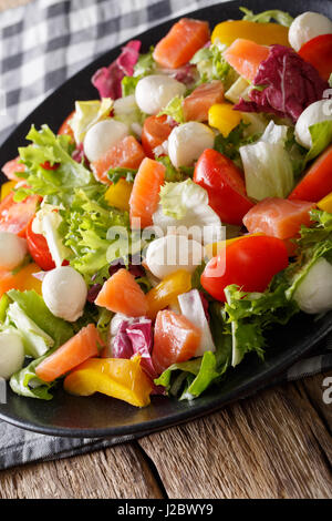 Köstlicher Salat mit Lachs, Mozzarella-Käse und Gemüse-Nahaufnahme auf einer Platte. Vertikal Stockfoto