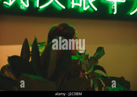 Bild der Frau im roten Kleid zugeschnitten, welche sitzen im lokal umgeben von Pflanzen. Ansicht von hinten Stockfoto