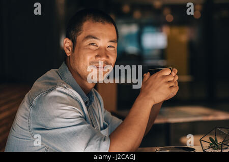 Lächelnd asiatischen Mann sitzt in einem Café Kaffee trinken Stockfoto