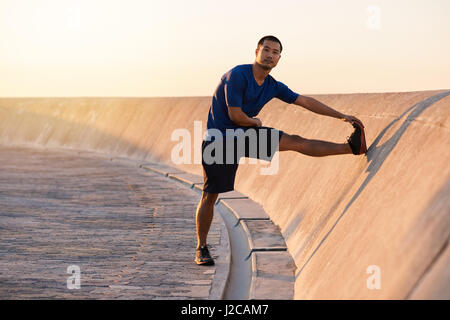 Jungen asiatische Mann seine Beine vor einem Lauf zu passen Stockfoto
