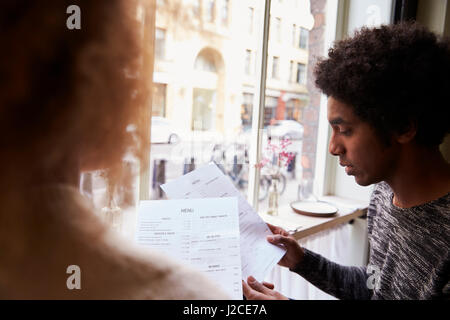 Junges Paar Blick auf Menüs im Restaurant City Stockfoto