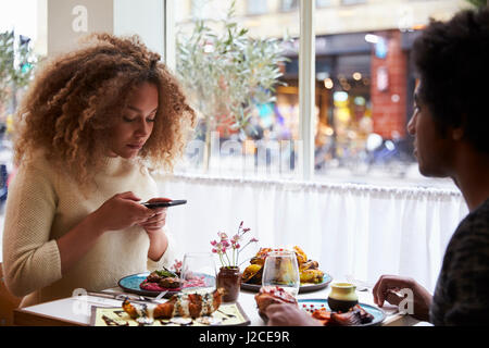 Food-Bloggerin, die Aufnahme der Mahlzeit im Restaurant auf dem Handy Stockfoto