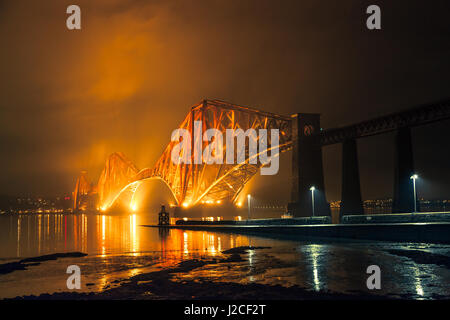 Die Forth Rail Bridge beleuchtet nachts. Goldenen Licht den Himmel oben. South Queensferry, Edinburgh, Schottland Stockfoto