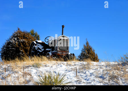 Antike Traktor sitzt draußen auf einem Hügel in Colorado.  Es ist rostig und verwittert.  Blauer Himmel rahmt es. Stockfoto