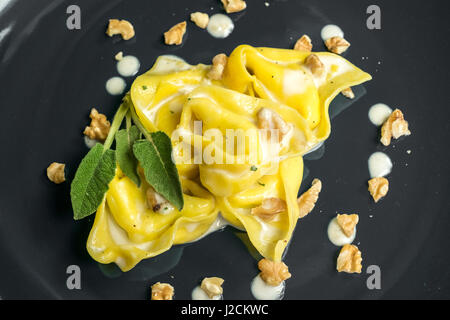 Tortelloni (hausgemachte gefüllte Nudeln) mit Nüssen, Sahne und Salbei. Bologna-Gastronomie. Stockfoto