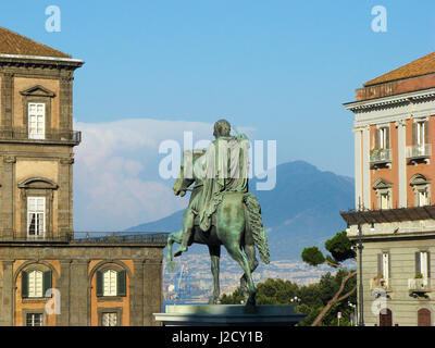 Piazza del Plebiscito, Neapel - Statua di Carlo III di Spagna (Carlo Sebastiano di Borbone) mit einem Teil des Vulkans Vesuv im Hintergrund Stockfoto