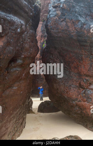 Fotograf Aufnahmen zwischen zwei großen Felsen am Strand Stockfoto