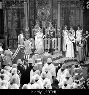 Die Seiten der Ehre heben Sie den Zug von Königin Elizabeth II Roben als sie und Prinz Philip, Duke of Edinburgh, nimmt ihre Hand, sie von ihrem Thron nach ihrer Rede bei der Parlamentseröffnung in der Kammer des House Of Lords zu erhöhen. Im Bild sind auch Prinzessin Anne (im Vordergrund rechts), ihr Ehemann Captain Mark Phillips (extreme Rechte), und The Sword of State, Marschall der Royal Air Force den Herrn Elworthy. Stockfoto