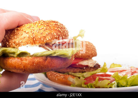 Hand hält frische Hamburger. Isoliert auf weißem Hintergrund Stockfoto