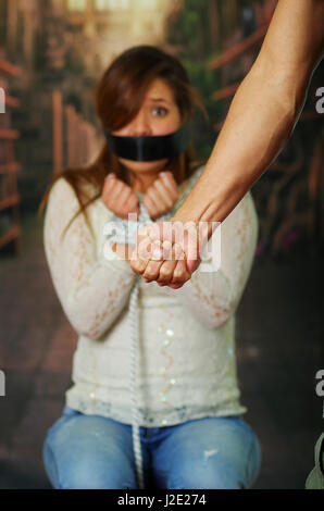 Männliche Faust gegen entführte junge Frau im Hintergrund Stockfoto