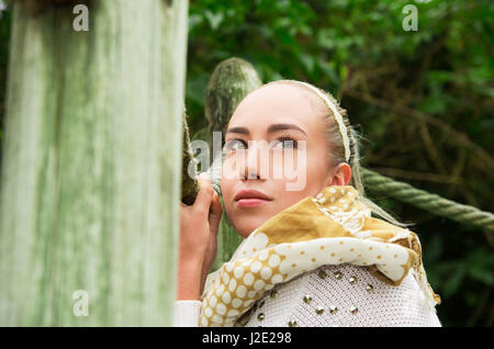 Schuss zu schließen, wenn junge blonde Mädchen sitzen in eine hölzerne Fußgängerbrücke Stockfoto