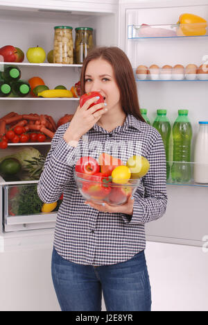 Gesunde Ernährung-Konzept. Ernährung. Schöne junge Mädchen in der Nähe der Kühlschrank mit gesunden Lebensmitteln. Obst und Gemüse in den Kühlschrank stellen. Veganes Essen Stockfoto