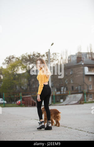 Schöne Blondine sah aus wie Jennifer Aniston steht mit Hund vor Hintergrund der städtischen Häuser Stockfoto