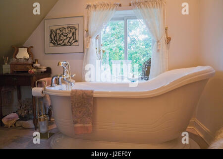 Antike Badewanne auf dem angehobenen Unterseite in das Bad in der oberen Etage in einem alten Landhaus Wohnhaus 1809 Stockfoto