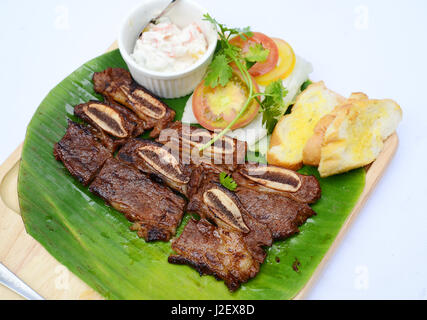 Gehackte Schweinerippchen mit Brot und Tomaten auf Banane Blatt Schale gegrillt Stockfoto