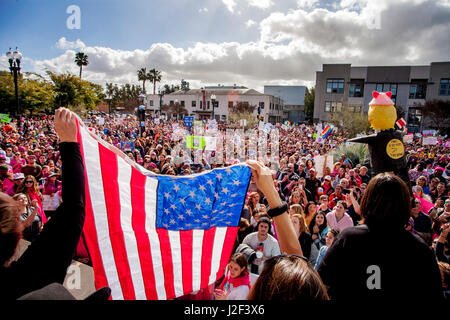 Eine amerikanische Flagge ist entfaltet vor der Menge auf den Januar 2017, Anti-Trump Frauen März in Santa Ana, CA. Hinweis Donald Trump Bildnis auf der rechten Seite. Stockfoto