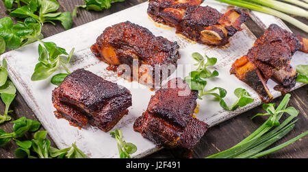 Gegrillte Spareribs mit frischen Kräutern auf Holzbrett serviert. Stockfoto