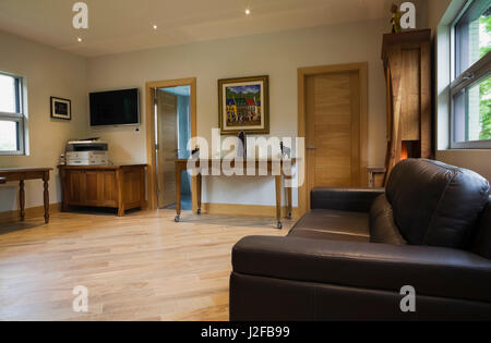Schwarzes Ledersofa und Kirschholz Tabellen in Büro, in einem modernen kubistischen Stil Wohnhaus Stockfoto