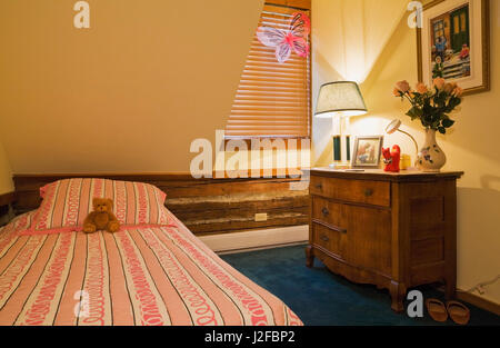 Einzelbett und alte hölzerne Kommode im Kinderzimmer in der oberen Etage in einem rekonstruierten Landhausstil 1976 Home anmelden Stockfoto