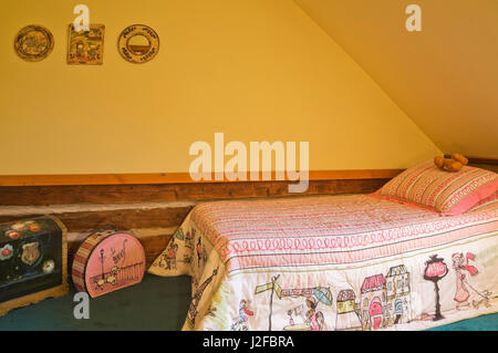 Einzelbett und alte Koffer im Kinderzimmer in der oberen Etage in einem rekonstruierten Landhausstil 1976 Home anmelden Stockfoto