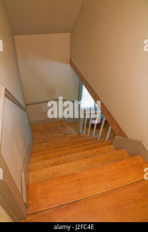 Holztreppe führt in die untere Etage in einem alten rekonstruierten Blockhaus im Stil von 1850er Cottage. Stockfoto