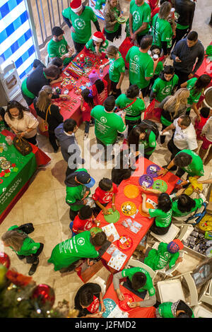 Gemischtrassige Weihnachten Feiernden Schar eine Handwerk Messe im jährlichen Urlaub Festival in einem Luxus-Einkaufszentrum in Costa Mesa, CA. Hinweis grünen t-Shirts. Stockfoto