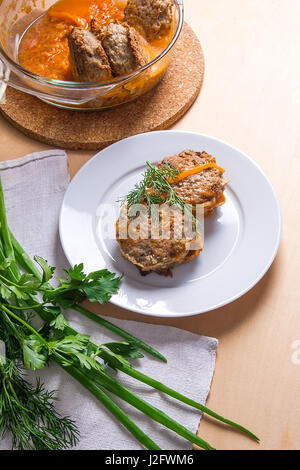 Frikadelle aus Schweinefleisch serviert auf einem weißen Teller und Kräuter - Dill, Frühlingszwiebeln, Petersilie um die Platte. Hausgemachte Frikadellen, gebraten mit Gemüse in Keramik Stockfoto