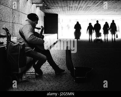 Straße Straßenmusiker / Musiker spielt eine Gitarre für Geld in einer Fußgängerunterführung in München, in der Nähe des englischen Gartens. Komposition in schwarz und weiß. 5 t Stockfoto