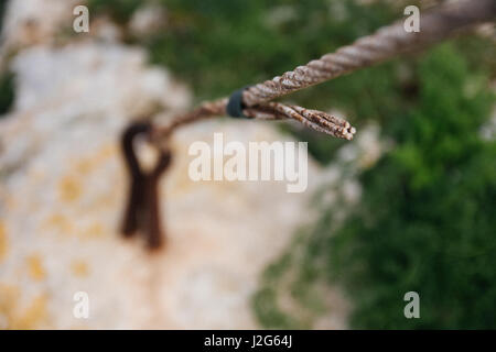 Rostiges Metall Kabel gebunden an eine Metallöse in den Boden Closeup verwischt. Stockfoto